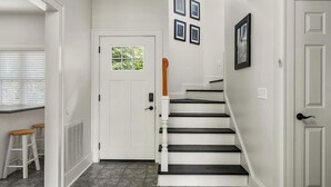 Ein heller Innenraum mit Treppe, weißen Wänden und einer Tür mit Fenster.