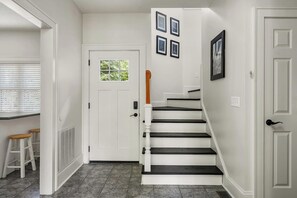 A white interior with a staircase, white walls, and a door with a window.