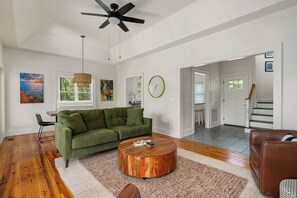 A spacious living room with a green sofa, a wooden coffee table, and a ceiling fan.
