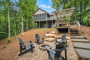 A cabin with a deck, outdoor seating, and a fire pit.