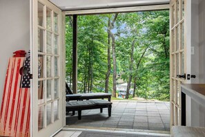 Une porte ouverte donnant sur un patio équipé d’un banc et décoré d’un drapeau.