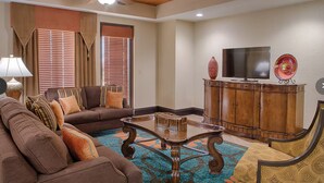 A living room with a sofa, armchairs, a coffee table, and a television on a wooden cabinet.