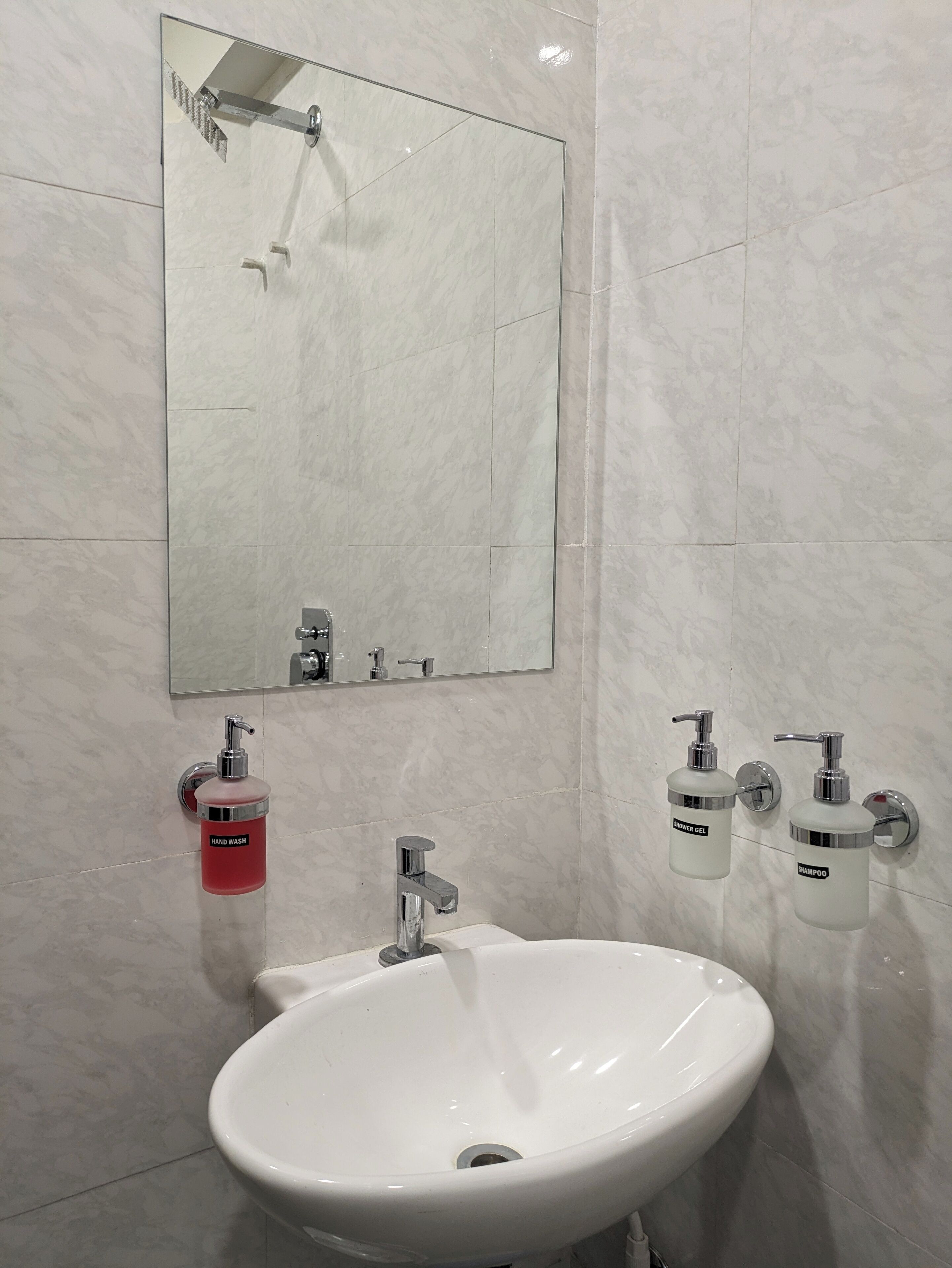 A bathroom with a white sink, a mirror, and two hand soap dispensers.