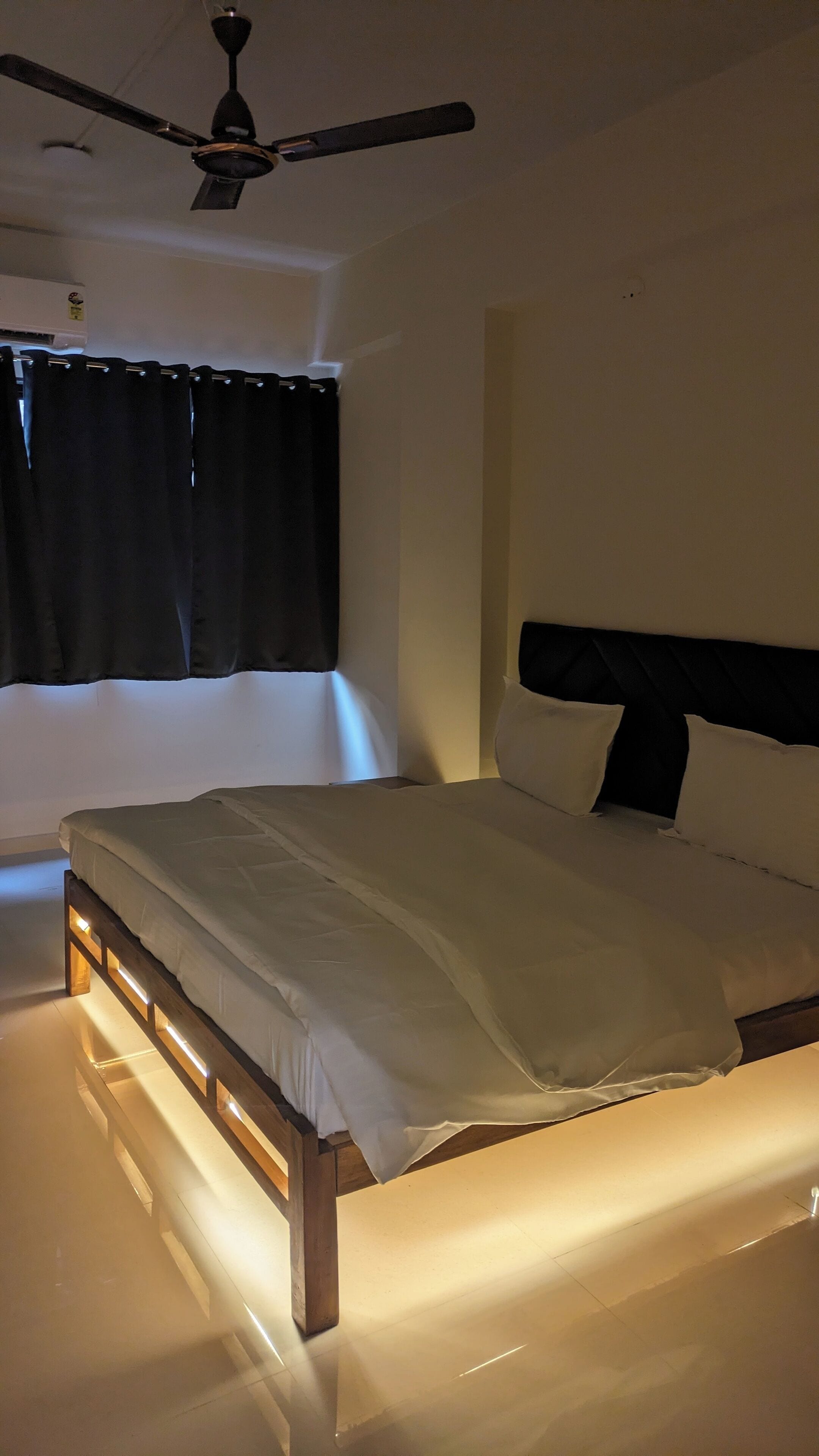 A bedroom with a bed, a ceiling fan, and a window with curtains.