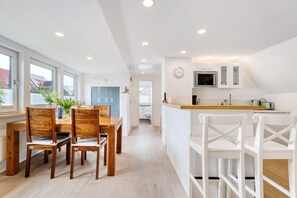 A modern kitchen with white cabinets, a microwave, and a clock on the wall. - Apartment 'Ferienwohnung Feuerbach' with Shared Terrace, Shared Garden and Wi-Fi (Telgte)