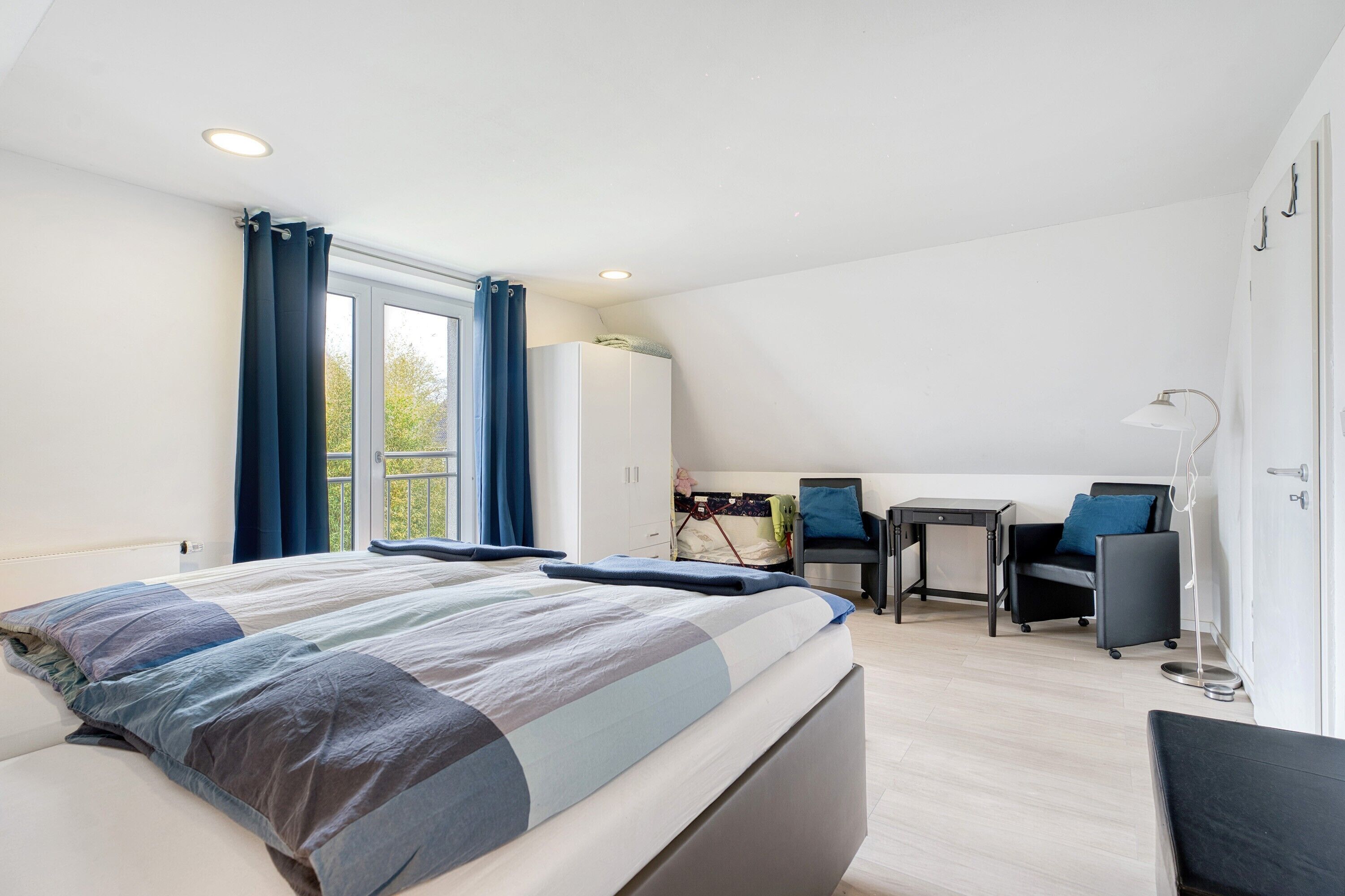 Una camera da letto moderna con un letto grande, una scrivania, una sedia, un armadio e vista sull'esterno.