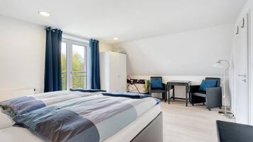 Una camera da letto moderna con un letto grande, una scrivania, una sedia, un armadio e vista sull'esterno.