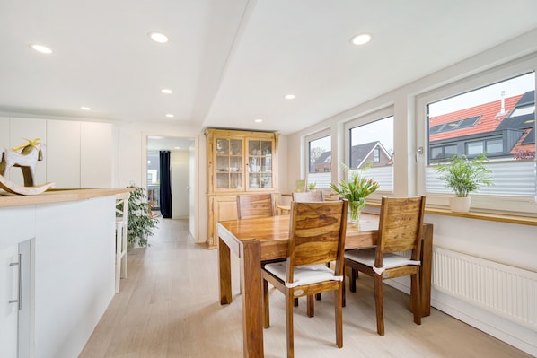 Una cocina moderna con armarios blancos, una mesa de comedor de madera y vistas al exterior.