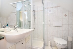 Ein Badezimmer mit Waschbecken, Spiegel, Dusche, Toilette und einer Duschkabine.