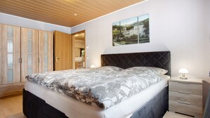 A bedroom with a bed, a nightstand, a dresser, and a painting on the wall. - Apartment 'K Schröder' with Private Terrace, Private Garden and Wi-Fi (Sundhagen)