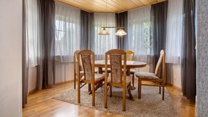 A dining area with a round table, wooden chairs, a rug, and a ceiling light fixture. - Apartment 'K Schröder' with Private Terrace, Private Garden and Wi-Fi (Sundhagen)