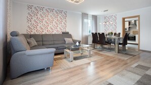 Ein modernes Wohnzimmer mit Sofa, Couchtisch, Esstisch und Stühlen.