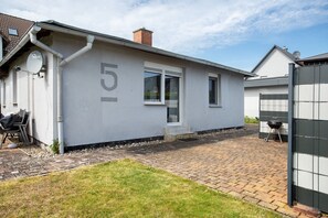 Una casa con il numero 5, un'antenna parabolica e un vialetto lastricato.