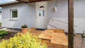 Ein Haus mit weißer Fassade, einer Haustür mit Glasfenster, einem kleinen Fenster und einem Blumentopf.