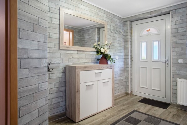 Un couloir avec une armoire en bois, un miroir et une porte blanche.