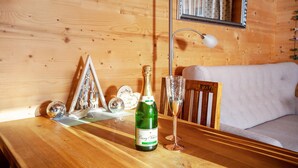 A wooden cabin interior with a wooden table, a bottle of wine, and a glass of wine. - Apartment 'Ferien Bei Mari' with Mountain View, Private Garden and Wi-Fi (Schwangau)