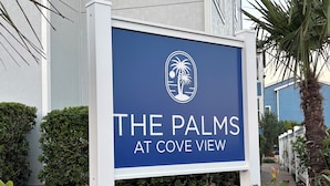Een bord met de tekst 'The Palms at Cove View' en een palmboomlogo.