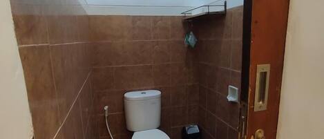 Un baño pequeño con inodoro, lavamanos y ducha.