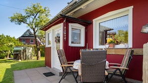 A red building with a window, a door, and a small table with chairs outside. - Apartment 'Fewo 32 - Halbinsel Darss - Ostsee' with Private Terrace, Shared Garden and Wi-Fi (Wieck am Darß)