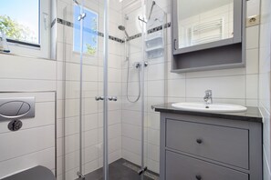 Une salle de bain moderne avec une douche à parois de verre, un lavabo et un miroir au-dessus du meuble-lavabo.