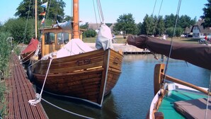 A wooden boat docked at a pier with a covered cabin and a small deck area. - Apartment 'Fewo 33 - Halbinsel Darss - Ostsee' with Private Terrace, Shared Garden and Wi-Fi (Wieck am Darß)