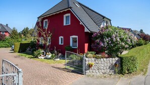 A red house with a stone wall and a metal gate. - Apartment 'Fewo 33 - Halbinsel Darss - Ostsee' with Private Terrace, Shared Garden and Wi-Fi (Wieck am Darß)