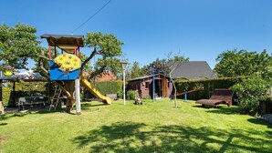 A backyard with a play structure, a slide, a swing set, and a small shed. - Apartment 'Fewo 33 - Halbinsel Darss - Ostsee' with Private Terrace, Shared Garden and Wi-Fi (Wieck am Darß)
