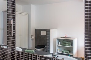 A bathroom with a white sink, a mirror with a black grid pattern, a toilet, and a shelf with towels.