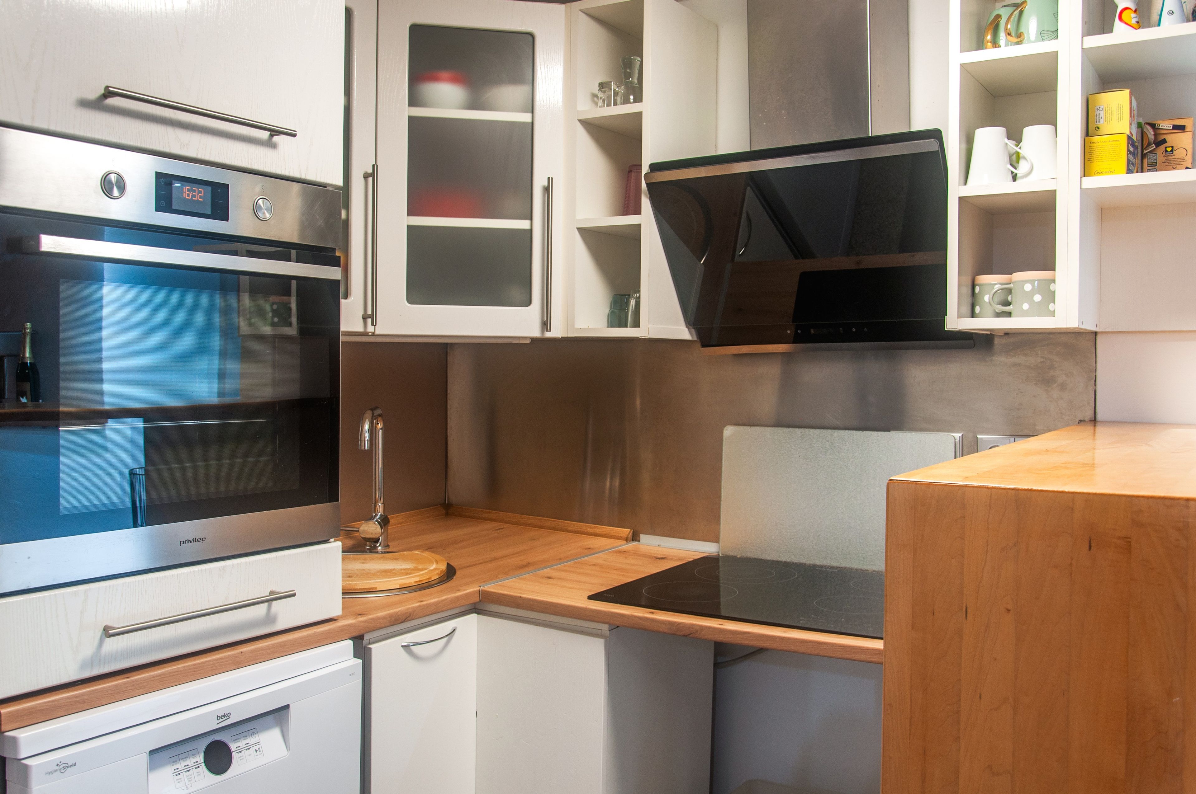 Une cuisine moderne dotée d’un four encastré, d’un four à micro-ondes et d’un plan de travail en bois.