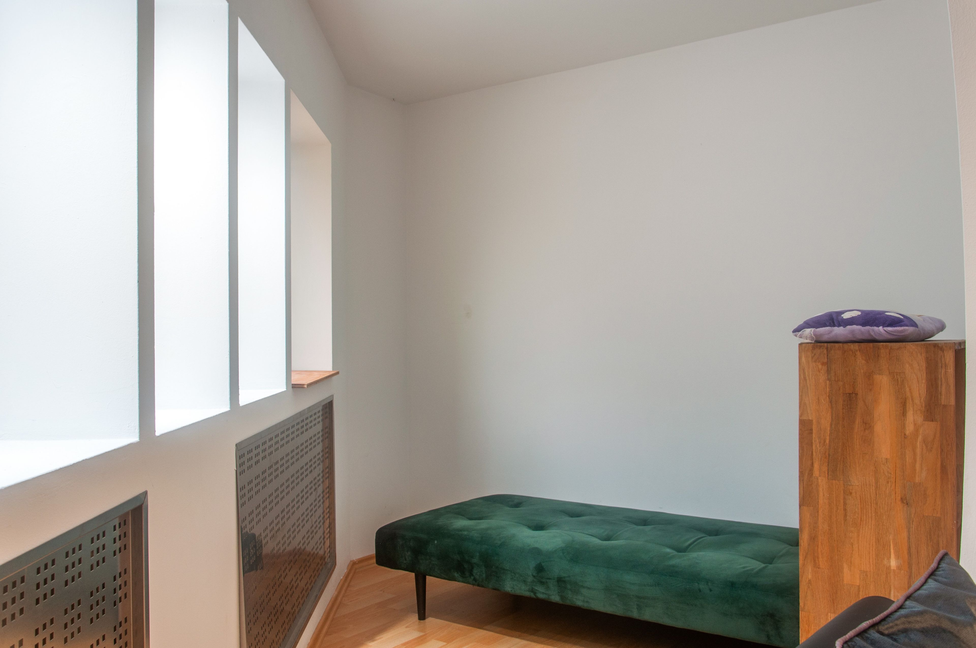 Una habitación con un banco tapizado en verde, un pilar de madera y un ventanal con vistas.