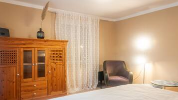 Une chambre à coucher avec une armoire en bois, une chaise, une table de chevet et une lampe.