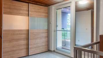Una habitación con puerta corredera que da a un espacio exterior, techo de madera y suelo de baldosas.