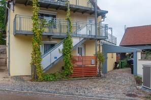 Un bâtiment à deux étages, doté d’un escalier, d’un balcon et d’une porte en bois.