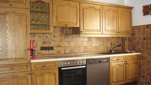 A kitchen with wooden cabinets, a tiled backsplash, a stove, an oven, and a dishwasher. - Apartment 'Ferienwohnung Sprang' with Shared Terrace and Wi-Fi (Steinen)