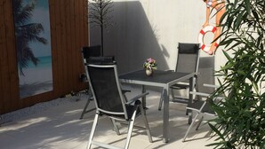 An outdoor patio with a table and chairs, a small plant, and a mural on the wall. - Apartment 'Ferienwohnung Sprang' with Shared Terrace and Wi-Fi (Steinen)