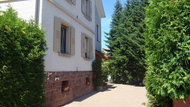 A building with multiple windows and a brick base, surrounded by greenery. - Apartment 'Ferienwohnung Sprang' with Shared Terrace and Wi-Fi (Steinen)