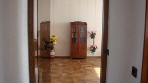 A hallway with a tiled floor, a wooden cabinet, and a vase with flowers. - Apartment 'Ferienwohnung Sprang' with Shared Terrace and Wi-Fi (Steinen)