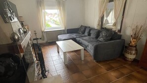 A living room with a sofa, a coffee table, a radiator, and a window with curtains. - Apartment 'Ferienwohnung Sprang' with Shared Terrace and Wi-Fi (Steinen)