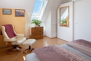 A room with a bed, a chair, a dresser, a mirror, and a skylight.
