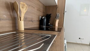 Une cuisine dotée de meubles en bois, d’un plan de travail en acier inoxydable et de divers ustensiles.