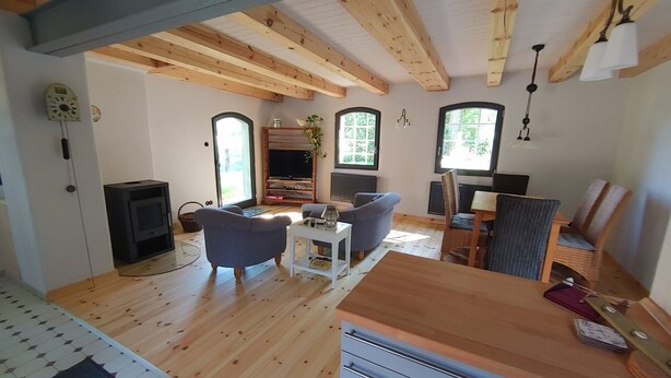 A cozy living room with a fireplace, sofa, and dining area. - Holiday Home 'Melkerhaus' with Private Terrace, Private Garden and Wi-Fi (Boitze-Neetzendorf)