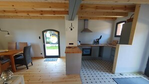 A kitchen with a stove, sink, and cabinets, a dining area with a table and chairs, and a door leading outside. - Holiday Home 'Melkerhaus' with Private Terrace, Private Garden and Wi-Fi (Boitze-Neetzendorf)