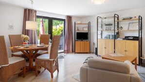A living room with a sofa, dining table, chairs, and a TV.