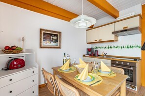 Ein Essbereich mit einem Holztisch, gedeckt für vier Personen, einem roten Toaster und einer weißen Wand mit einem gerahmten Gemälde.