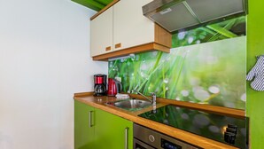 Uma cozinha compacta com pia de aço inoxidável, cafeteira e micro-ondas.
