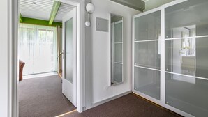 Um interior moderno com piso carpetado, uma porta com painéis de vidro jateado e uma parede verde de destaque.