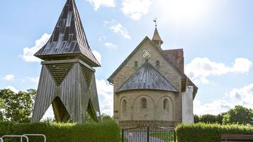 A church with a clock tower and a modern structure with a pointed roof.