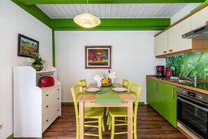 A compact kitchen with a dining table, chairs, a refrigerator, and a stove. - Apartment 'Atlanta  101' with Private Terrace, Private Garden and Wi-Fi (Pellworm)
