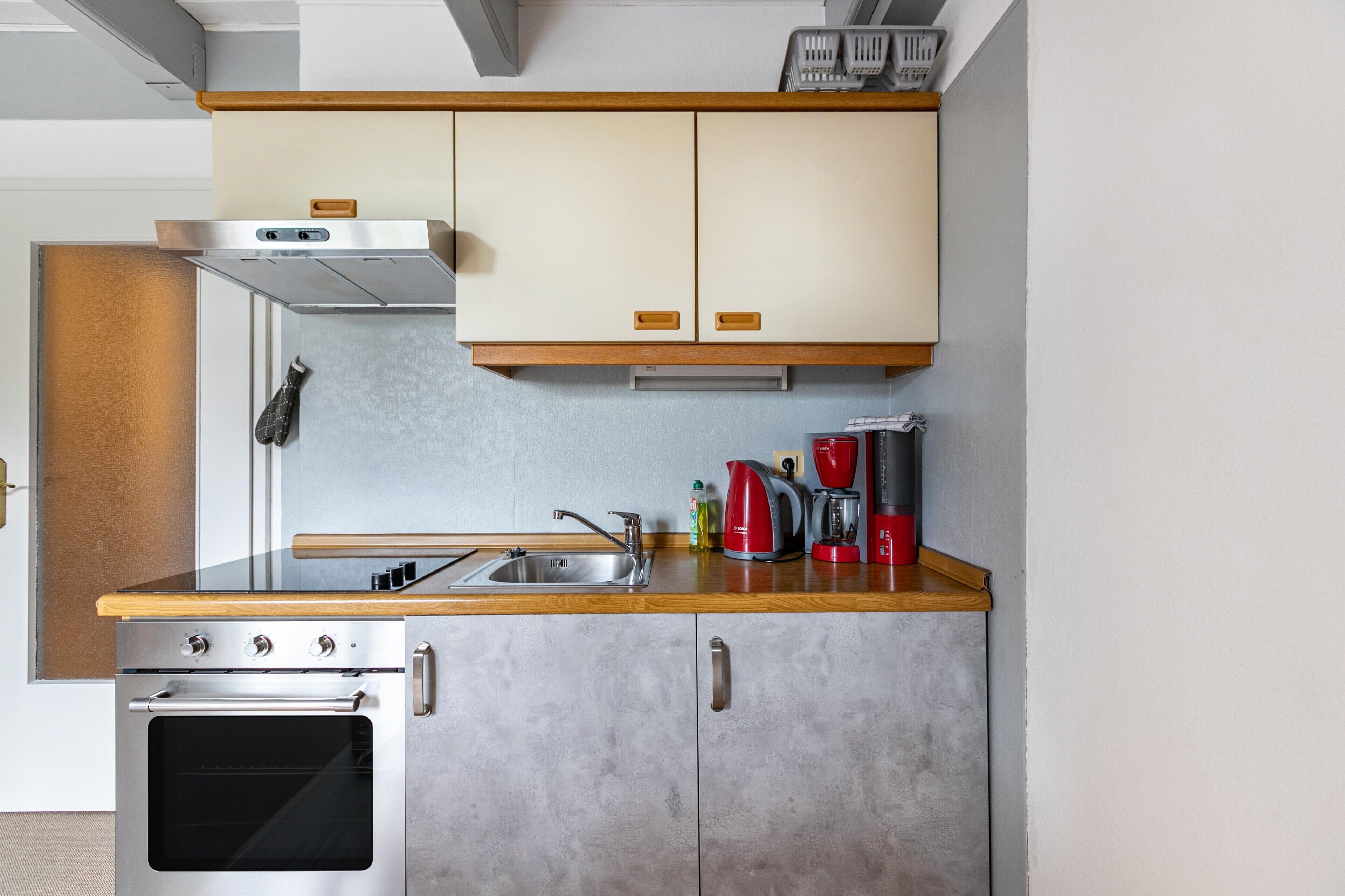 A compact kitchen with a stainless steel oven, a sink, and wooden countertops.