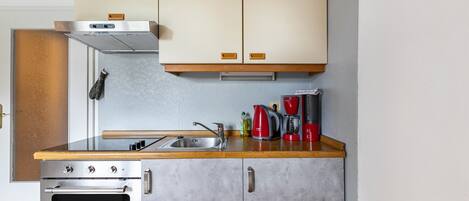 A compact kitchen with a stainless steel oven, a sink, and wooden countertops.
